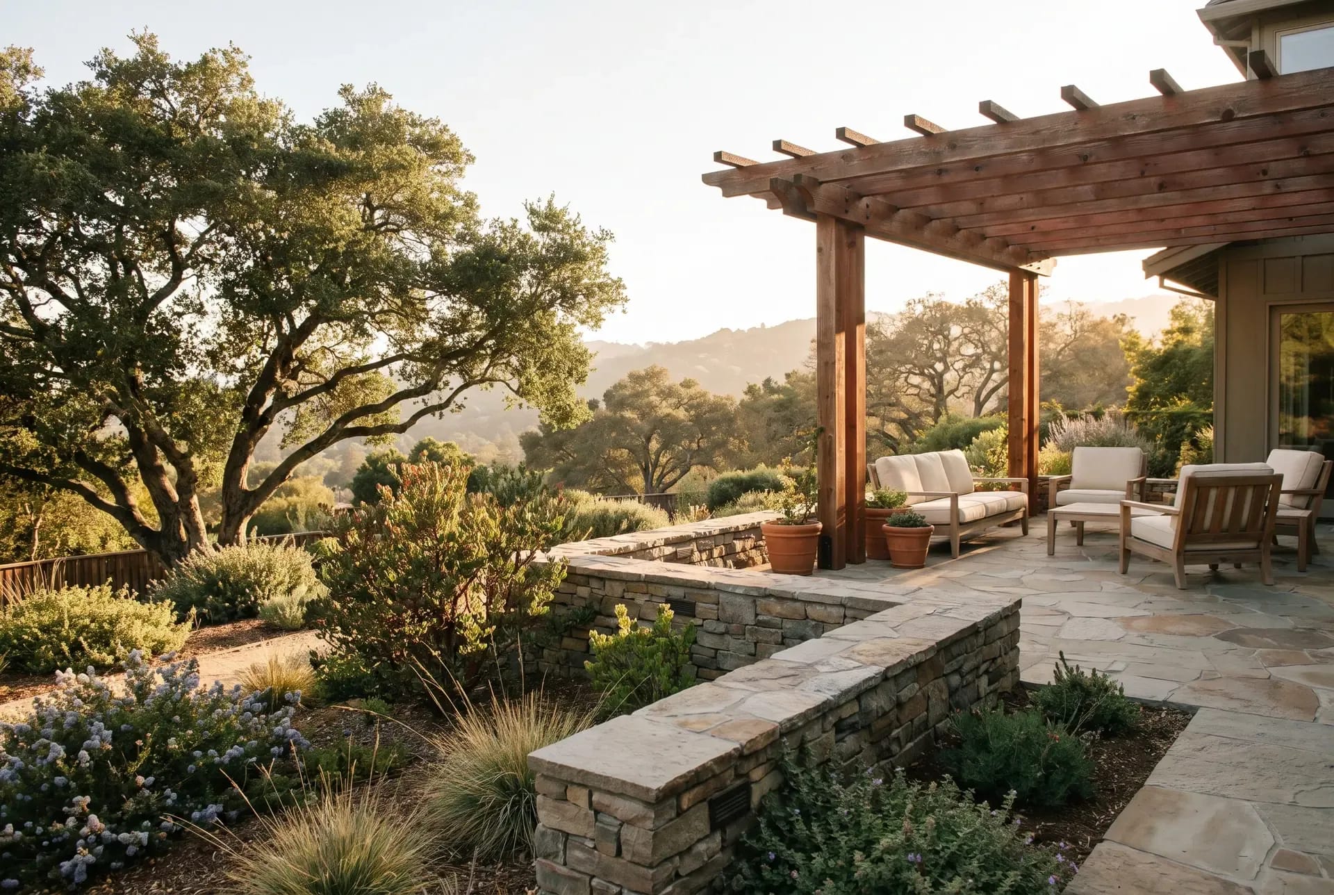 A terraced hillside backyard in Los Gatos with retaining walls, native oaks, and a patio overlooking a valley view