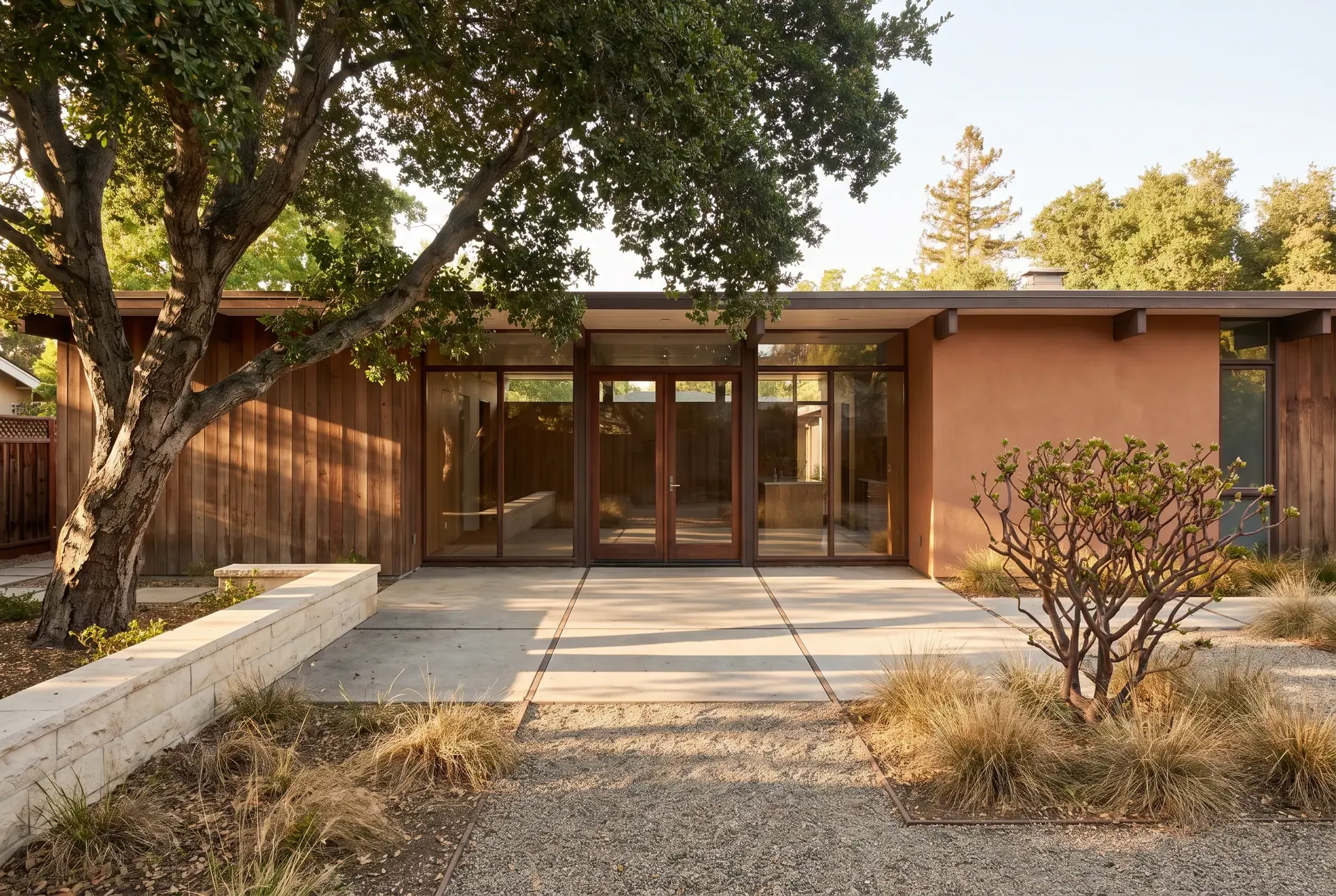 A mid-century modern Eichler-style home with floor-to-ceiling glass opening onto a clean-lined backyard patio with heritage oak and simple landscaping